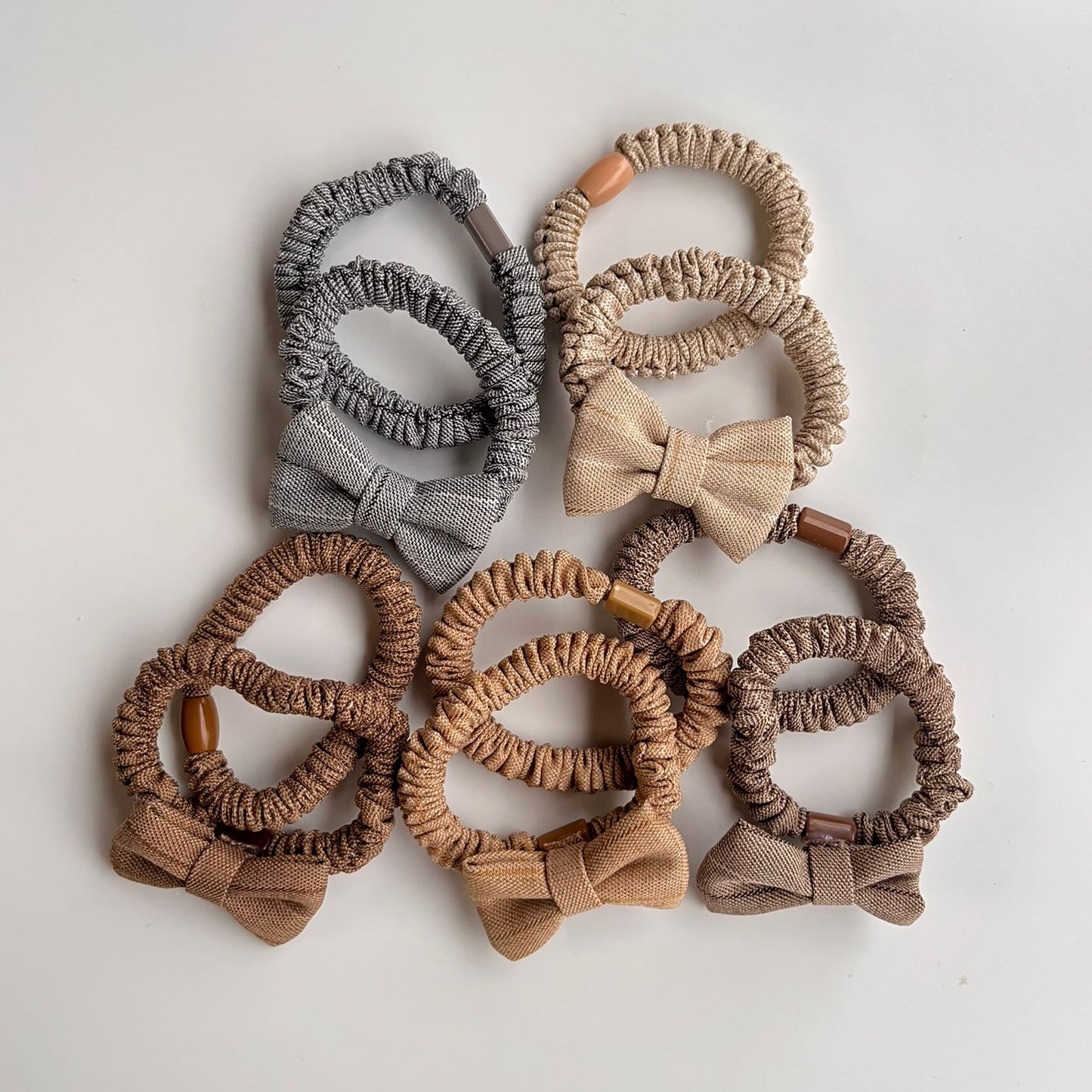 Set of hair scrunchies with bows in various shades of brown on a light background