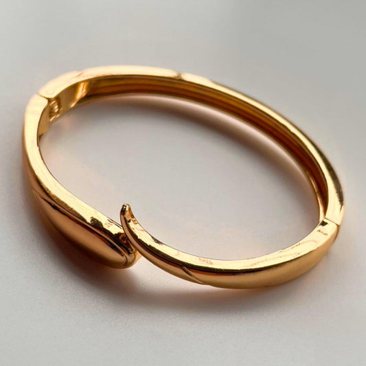 Gold bracelet on a light gray background