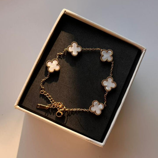 Bracelet with clover-shaped charms in a box on a light background