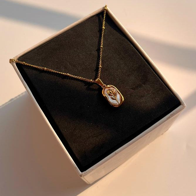 Gold necklace with a pendant in a black jewelry box on a light surface