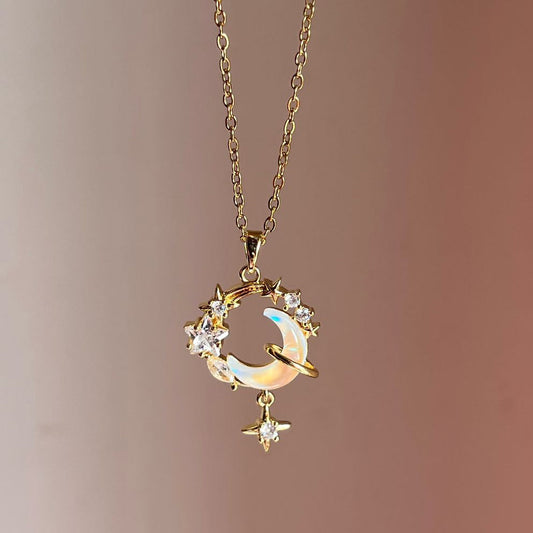 Delicate gold necklace with a moon and star pendant on a soft pink background