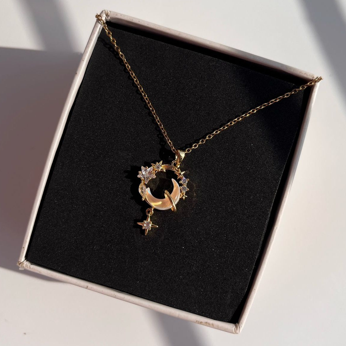 Gold necklace with a star pendant on a black box