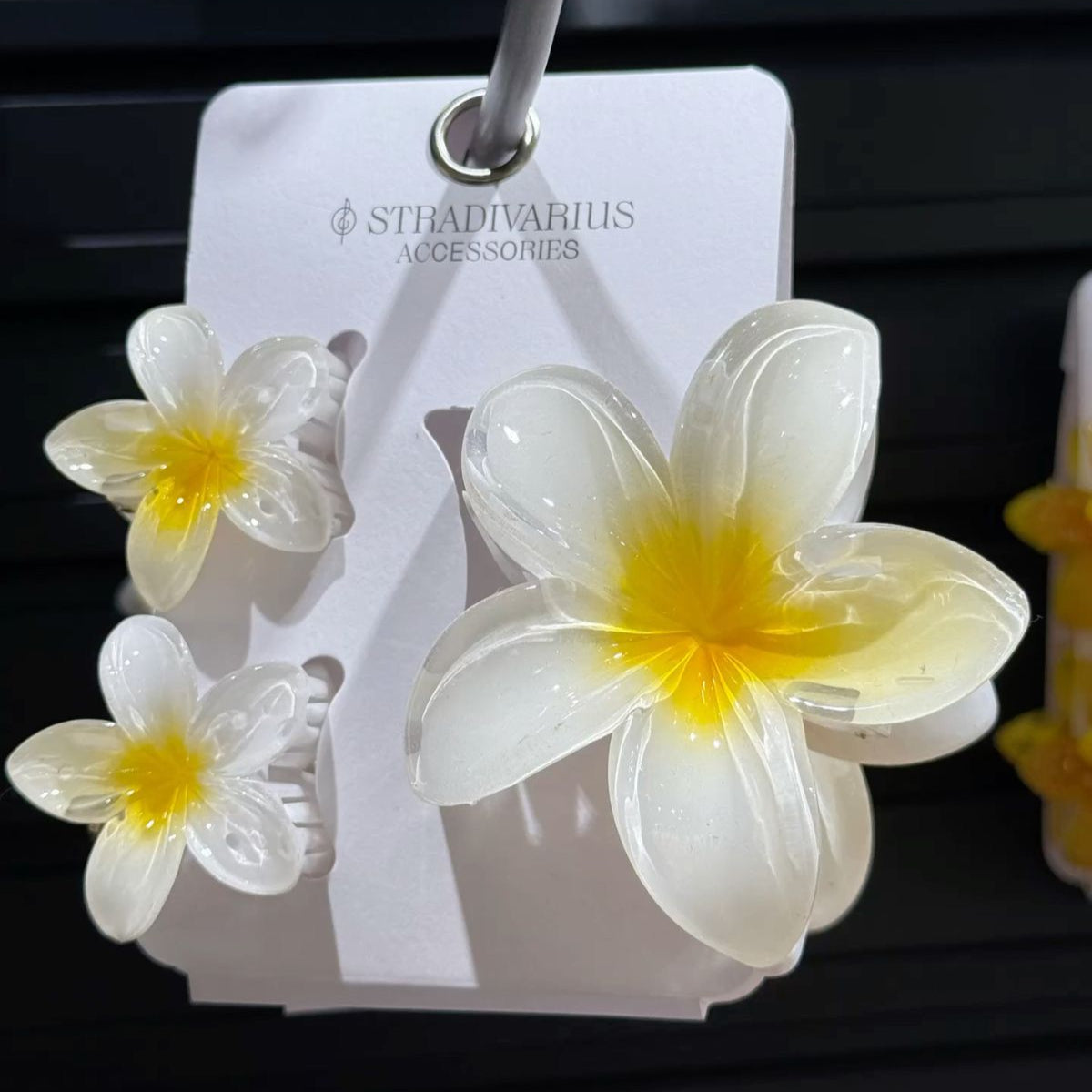 Flower-shaped earrings on a Stradivarius card against a dark background