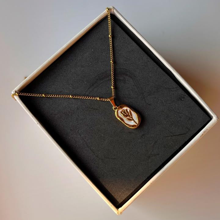 Gold necklace with a pendant in a black jewelry box on a light gray background